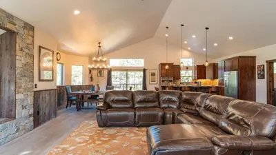 a living room with a leather couch and a stone wall at 10mins to Lake • Hot Tub Game Room Forest Views Meyers Meadow by AvantStay in South Lake Tahoe