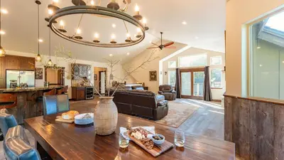 a kitchen and living room with a wooden table and a chandelier at 10mins to Lake • Hot Tub Game Room Forest Views Meyers Meadow by AvantStay in South Lake Tahoe