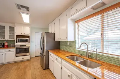 a kitchen with white cabinets and a stainless steel refrigerator at Royal Arches Cottages in Oakhurst