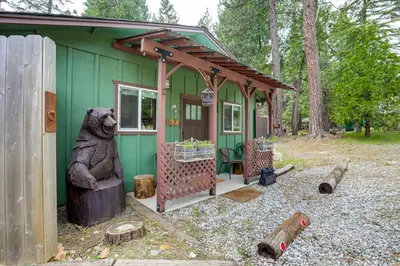 a green house with a bear statue in front of it at Cozy Cottage with Park Pass, 1 Mi to Jenkinson Lake! in Pollock Pines