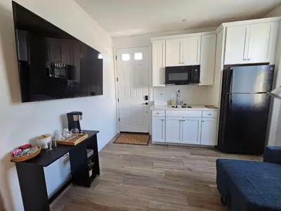 a kitchen with white cabinets and a black refrigerator at Couple's Getaway Kitchenette Washer & Private Bath in Lincoln Village