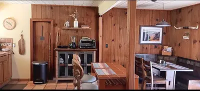 a kitchen with wooden walls and a table with chairs at 1948 Cottage with today's amenities in Bass Lake Annex