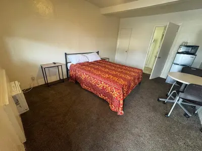a bedroom with a bed and a table and a desk at The Oaks Motel in Gilroy