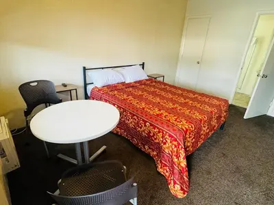 a bedroom with a bed and a table and a table and chairs at The Oaks Motel in Gilroy