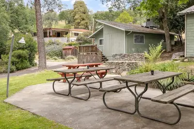 a picnic table and benches in front of a house at The General Sherman Cabin in Three Rivers