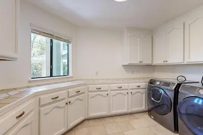 a kitchen with white cabinets and a washer and dryer at Fair Days on the Fairway in Groveland