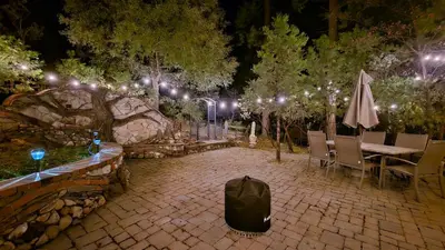 a patio with a table and chairs and lights at Knotty Pine Cabin with Artisan Stone Patio - Walk to Bass Lake in Bass Lake