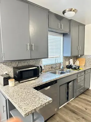 a kitchen with gray cabinets and a sink and a microwave at Casa de descanso in Visalia