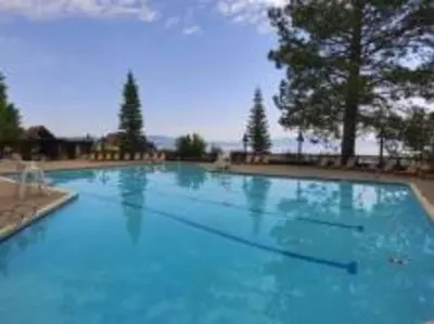 a large blue swimming pool with trees in the background at Newly Renovated Family Lake House, Private Beach! in Tahoma