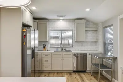 a kitchen with white cabinets and a sink at Quaint Hughson Vacation Rental, Walk to Downtown! in Hughson