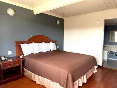a bedroom with a large bed with a wooden headboard at Regency Inn Fresno in Fresno