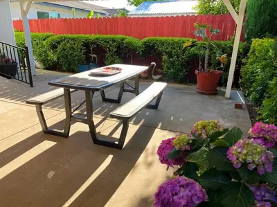 a picnic table and a bench on a patio with flowers at Spacious 2Beds Suite Close to Downtown and UC Davis Medical Center in Sacramento