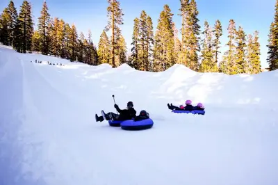 three people are riding down a snow covered slope on snowboards at Bigwood 54 K in Mammoth Lakes