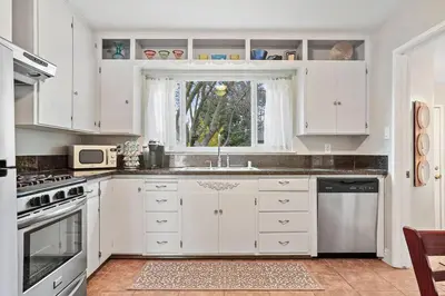 a white kitchen with a sink and a window at Robert St Cottage, near Lodi Lake in Lodi