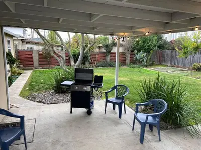 a patio with chairs and a piano under an umbrella at Robert St Cottage, near Lodi Lake in Lodi