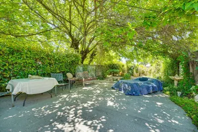 a patio with a table and chairs under a tree at Auburn Cottage with Patios and Garden - 3 Mi to Town! in Auburn