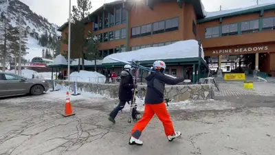 two people walking down a street with skis at 2BR Mins to Alpine Base Area Palisades! in Alpine Meadows