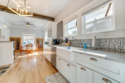 a kitchen with white cabinets and a wooden floor at Walk to Midtown Charming Reno Retreat in Reno