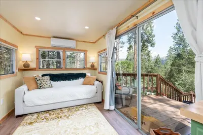 a living room with a couch and a balcony at Tiny home with spa/firepit/and more in Oakhurst