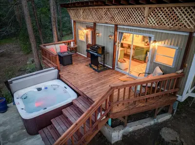 a large deck with a hot tub on a house at Tiny home with spa/firepit/and more in Oakhurst