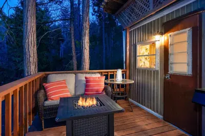 a screened porch with a couch and a fire pit at Tiny home with spa/firepit/and more in Oakhurst