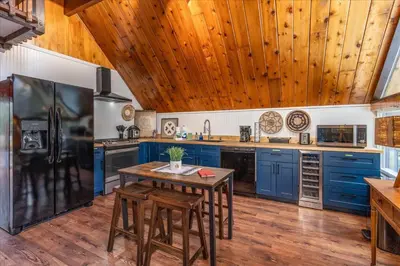 a kitchen with blue cabinets and a wooden ceiling at Bass Lake Chalet- A frame with hot tub/firepit in Oakhurst