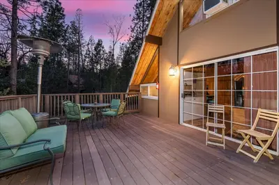 a deck with chairs and a table on a house at Bass Lake Chalet- A frame with hot tub/firepit in Oakhurst