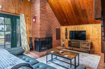 a living room with a couch and a fireplace at Bass Lake Chalet- A frame with hot tub/firepit in Oakhurst