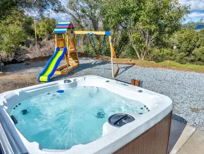 a jacuzzi tub with a slide and a playground at Mountain View House with hot tub, putting green, stunning views in Oakhurst
