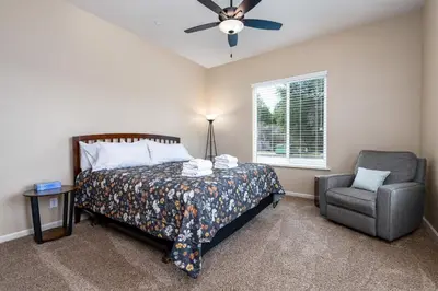 a bedroom with a bed and a chair and a ceiling fan at Mountain View House with hot tub, putting green, stunning views in Oakhurst
