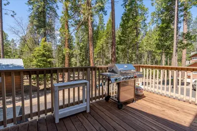 a grill on a deck with trees in the background at Base Camp- Inside Yose w pool table/grill in North Wawona