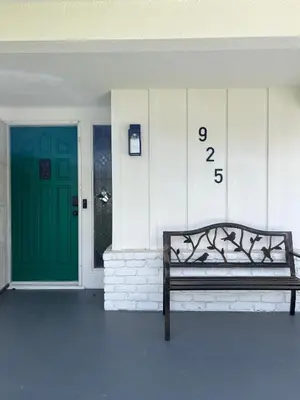 a bench in front of a building with a green door at Homey Pool Fun Gameroom Sunnyside Retreat in Fresno