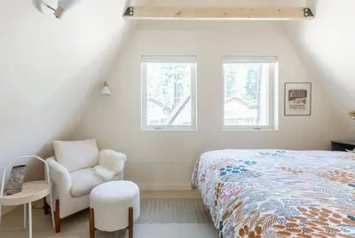 a bedroom with a bed and a chair and two windows at Brand New Modern A-Frame In Kings Beach Two Blocks From The Beach in Kings Beach