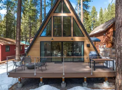 a cabin in the woods with a large deck at Brand New Modern A-Frame In Kings Beach Two Blocks From The Beach in Kings Beach