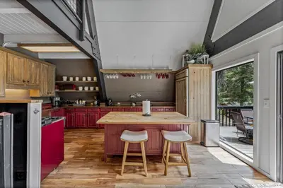 a kitchen with red cabinets and a wooden island with stools at 5BR A Frame Near Patton Beach with 2 Decks in Carnelian Bay