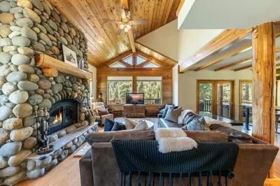 a living room with a large stone wall at Horizon at Tahoe Donner w Private Hot Tub and Mountain Views in Truckee