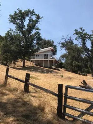 a dog sitting behind a fence in front of a house at Loyah Cabin in Ahwahnee