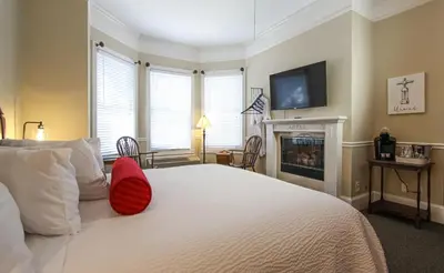 a bedroom with a white bed with a red pillow on it at The Inn at 161 in Sutter Creek