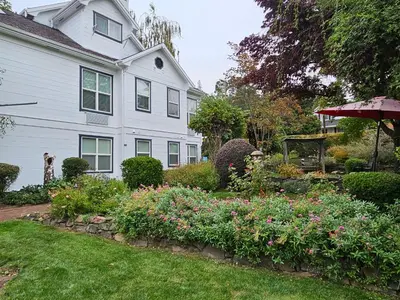a white house with a garden with flowers at The Inn at 161 in Sutter Creek