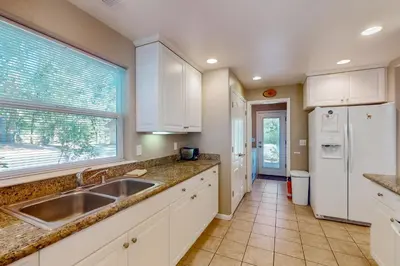 a kitchen with white cabinets and a sink and a window at Creekside & Cozy in Bass Lake