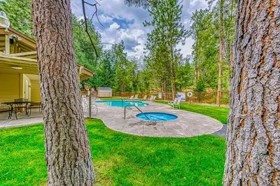 a backyard with a pool and a table and trees at Creekside & Cozy in Bass Lake