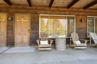 a porch of a cabin with two chairs and a table at Mountain Nook CN Lodge #4 in Ponderosa