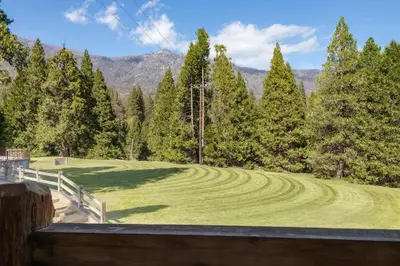 a field of grass with trees and mountains in the background at Camp Nelson Lodge Room 10 in Ponderosa