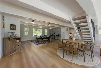 a living room with a dining table and a staircase at Lakefront Cottage at Lakewood in Auburn