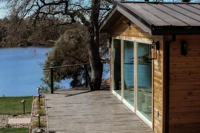 a small cabin with a wooden walkway next to a lake at Treehouse Overlook at Lakewood in Auburn