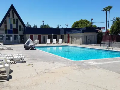 a swimming pool with chairs and a building at Economy Inn Fresno Yosemite in Fresno