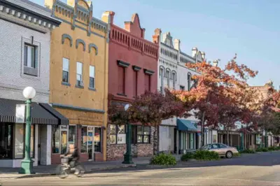 a person riding a bike down a street with buildings at Mid Century Wineries Game Room in Lodi