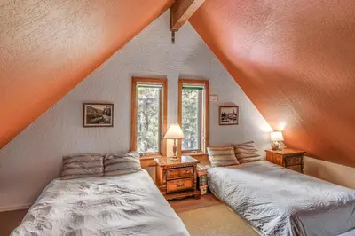 a attic bedroom with two beds and a window at Game Room and Hot Tub Serene Grand Mountain Chalet! in Stateline