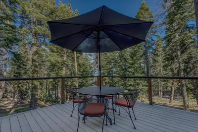 a table and chairs on a deck with an umbrella at 3BR with Sauna & Lake Views, 2 miles to Beach in Tahoe City