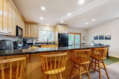 a kitchen with wooden cabinets and a counter with bar stools at Fire Pit, Near Lake Evergreen Escape in Arnold in Arnold